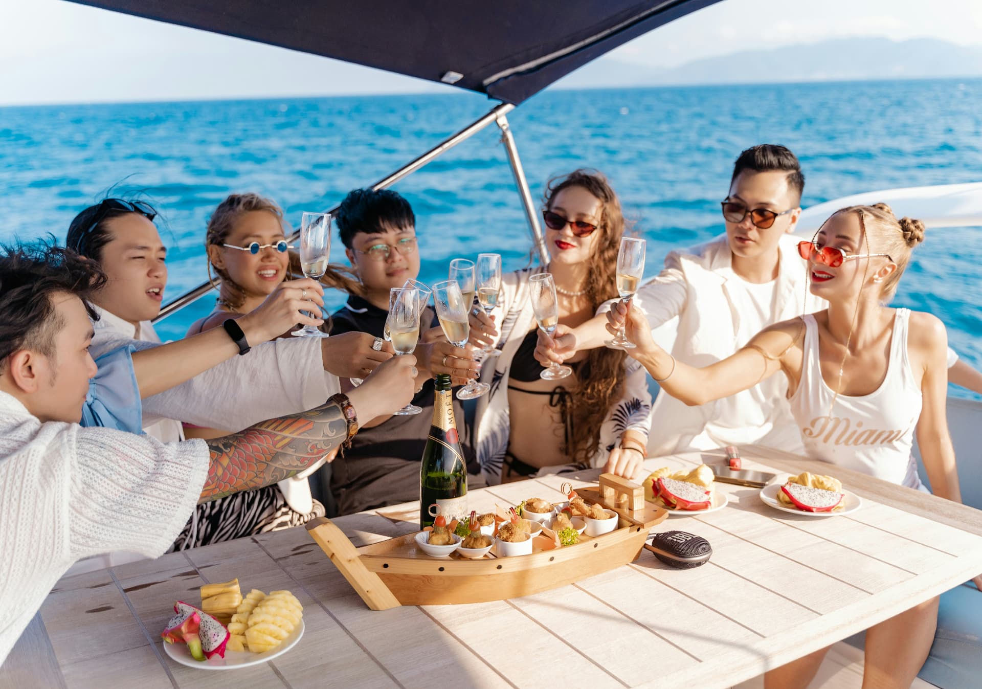 A group raising glasses on the deck of a boat in bright daylight